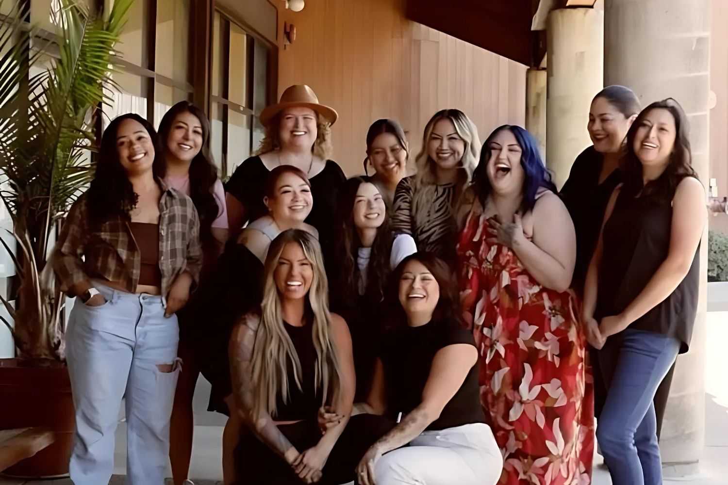Group of smiling people posing outdoors near a building.